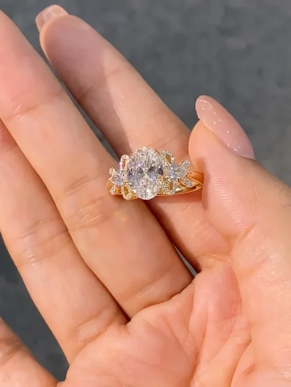 A ring featuring a 2-carat oval lab-grown diamond as the center stone, with a bow-shaped design on the band; graded as D color and VS1 clarity